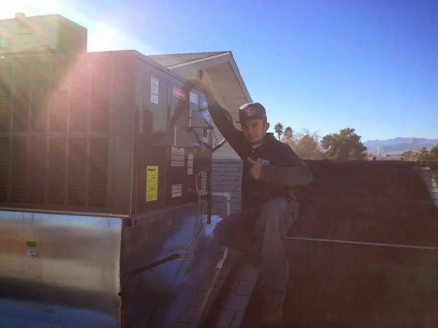 HVAC technician performing AC Tune-Up on a rooftop unit in D'Iberville